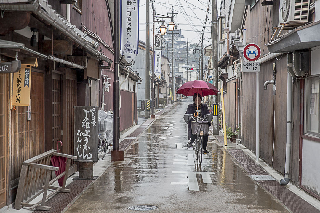 A Iga à vélo, avec un parapluie et des manches chauffantes