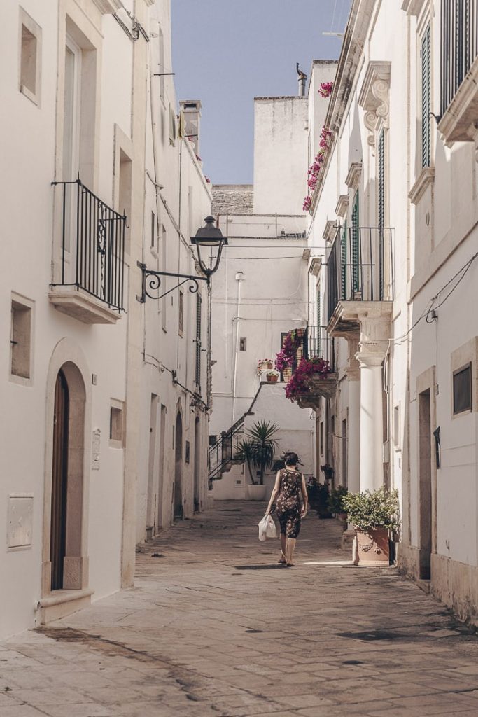 Femme revenant des courses dans les ruelles peu animées de Locorotondo
