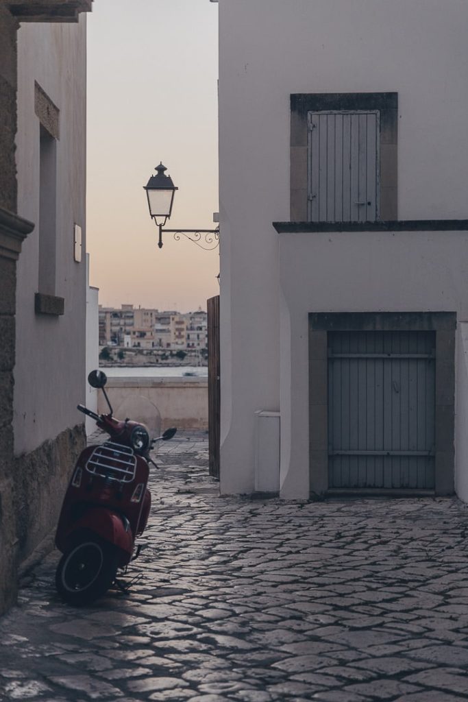 Ruelle pavée d'Otrante avec un vespa garé