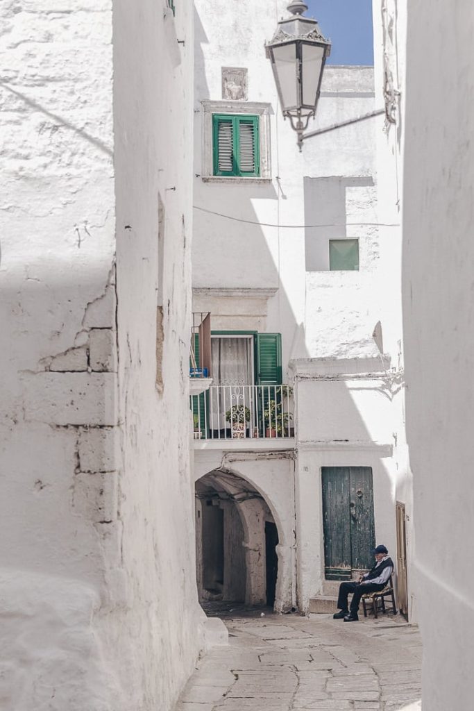 Personne âgée faisant la sieste dans les ruelles blanches pavées d'Ostuni