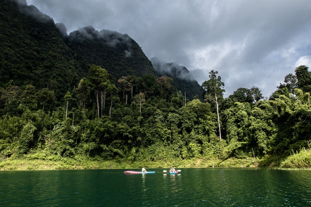 deux canoes sur un lac situé au pied de montagnes karstiques à la végétation luxuriante