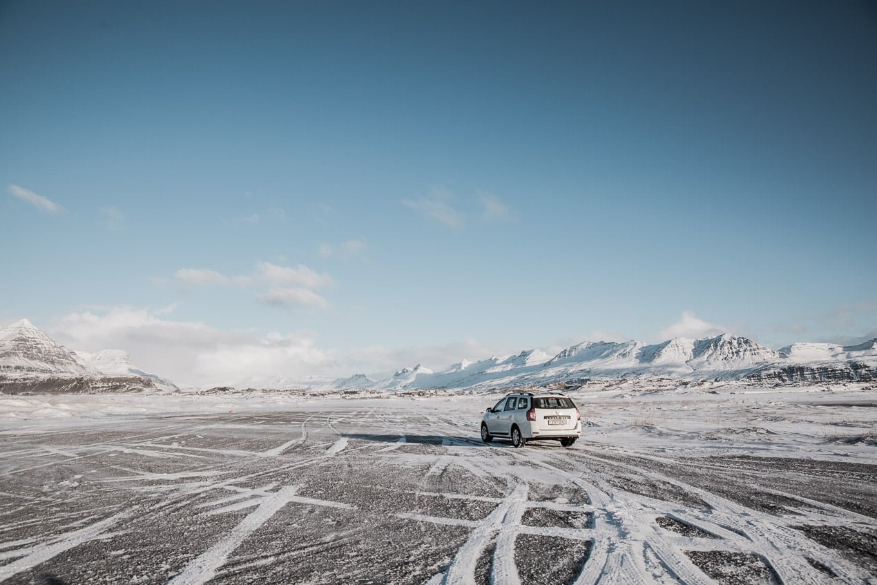 Dacia logan sur les routes d'islande enneigées en hiver sous un ciel bleu clair