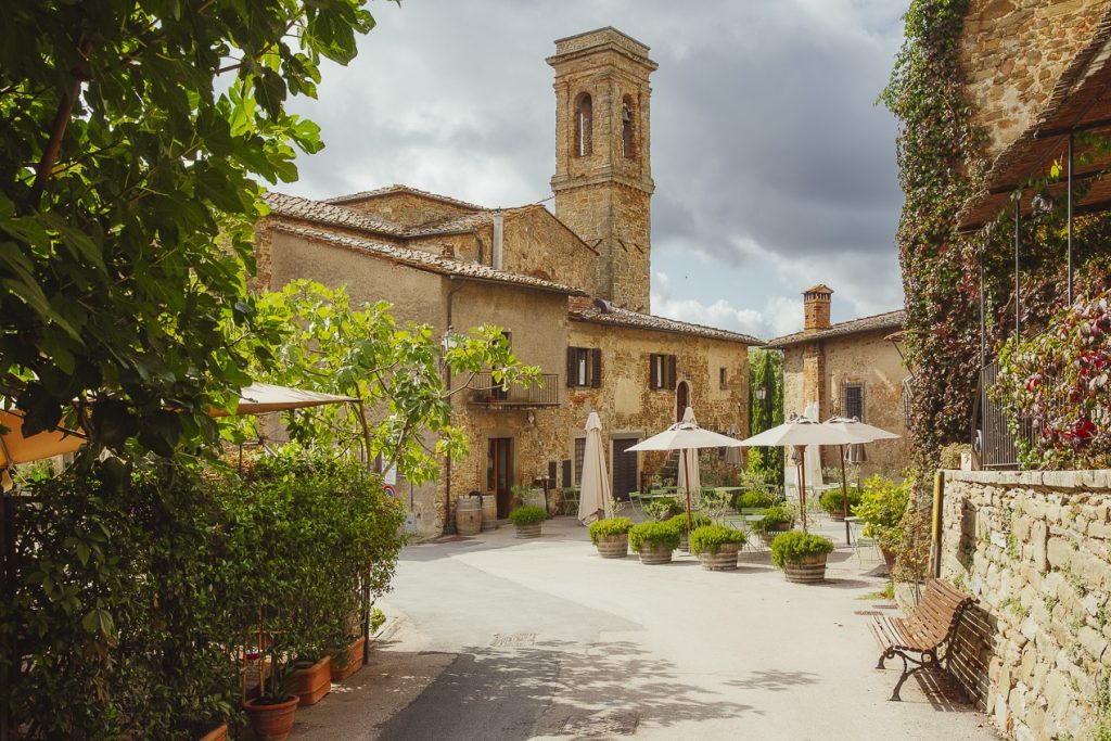 Charmante place fleurie à Volpaia, l’un des plus beaux villages du Chianti avec clocher en pierre et terrasses ombragées