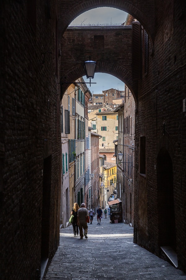 Ruelle pavée typique de Sienne aux teintes chaudes, dans le centre historique médiéval de la ville