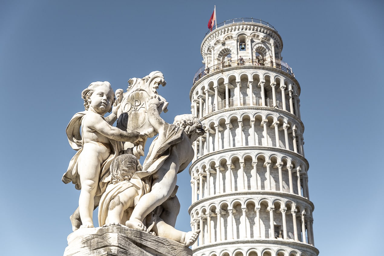 Statue baroque en marbre avec la Tour de Pise en arrière-plan, une des photos les plus prisées à faire quand on vient visiter Pise